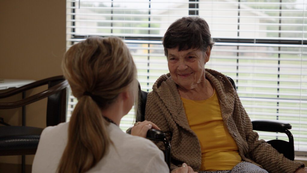 A long term care resident smiles at a nurse
