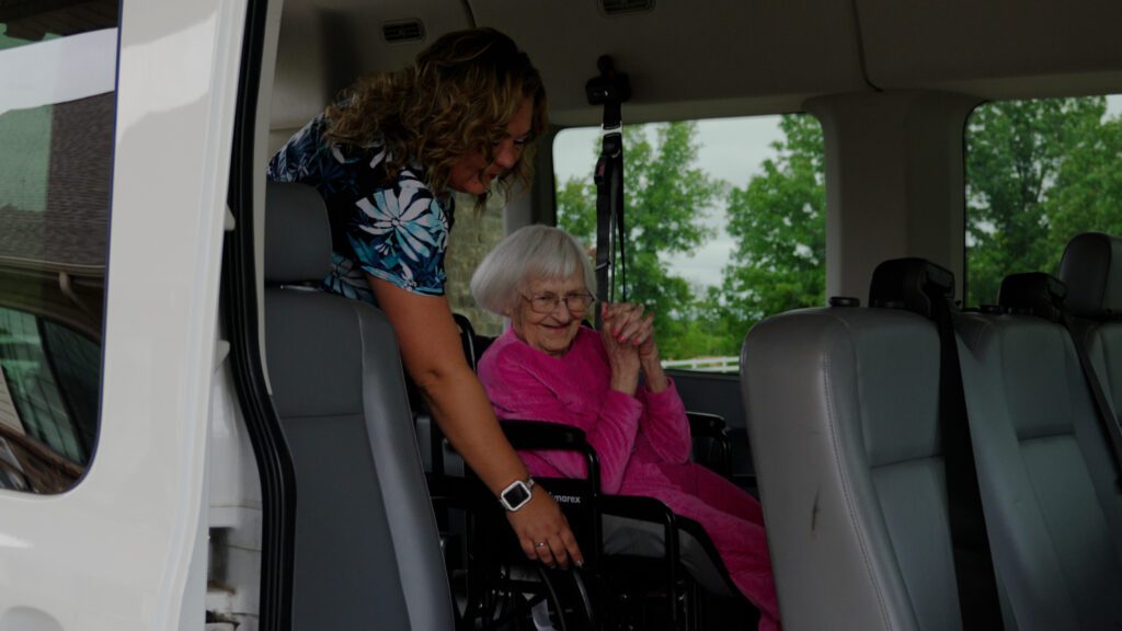 A woman smiles as she gets out of a van while using the respite care service