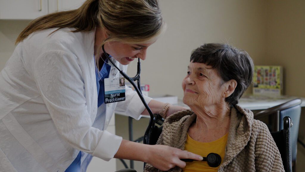 A nurse smiles at a resident at a skilled nursing care facility
