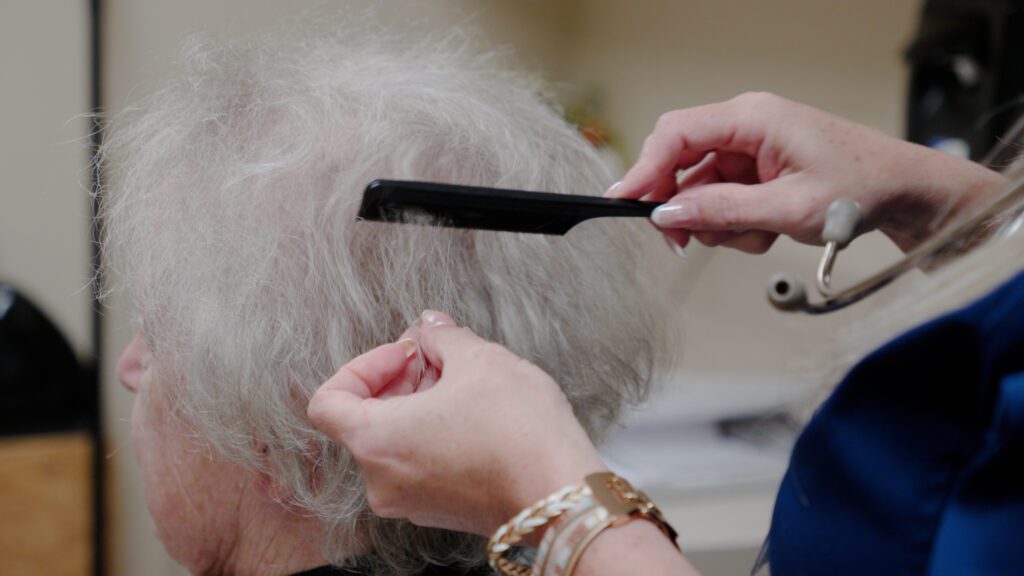 A woman getting her hair styled by a stylist at a skilled nursing facility