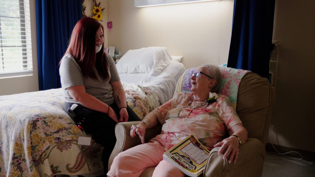 A nurse smiles at a resident at a skilled nursing nursing home